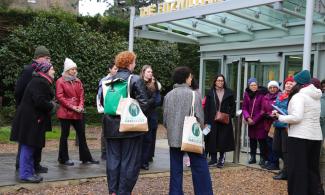 A group of people standing outside the entrance of the Fitzwilliam Museum facing a tour guide.