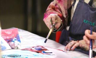 A person participating in a painting workshop at Kettle's Yard.