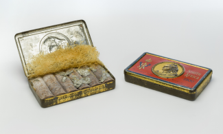 Queen Victoria's New Year chocolate tin, including a red and gold tinplate, yellow shredded paper and discoloured chocolate.