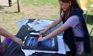 Child using a screen to print her design onto a t-shirt