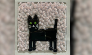 A fused glass square with a cat on it 