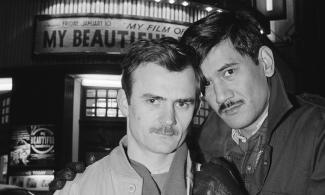Black and white photo of two men stood in front of cinema
