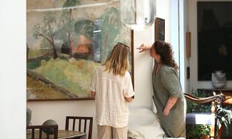 Two people looking at a large landscape painting in the Kettle’s Yard house, one gesturing towards it.