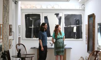 Two people viewing artworks in the Kettle’s Yard house, looking towards a display of paintings, sculptures and ceramics.