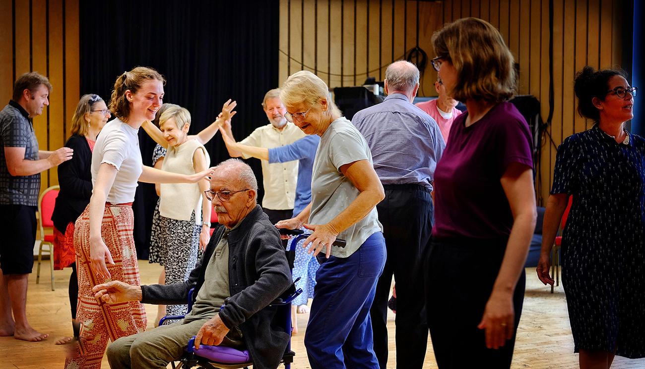 A group of people stand and dance together in a room at Cambridge Junction.