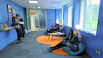 Students stand and sit in the Rise Up Reflection space, some on beanbags.