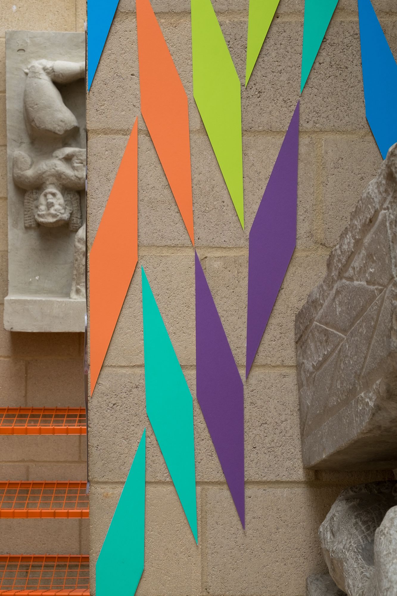Coloured mountboard cut into rhombus shapes arranged on a wall