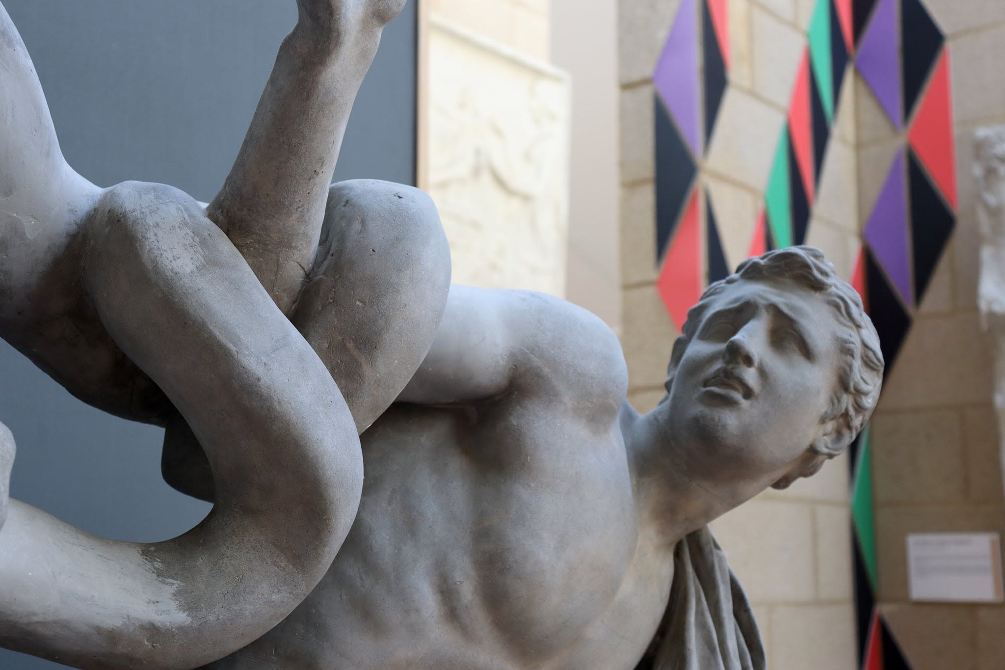 geometirc shapes snaking up the wall behind a cast of a boy being entangled by snakes