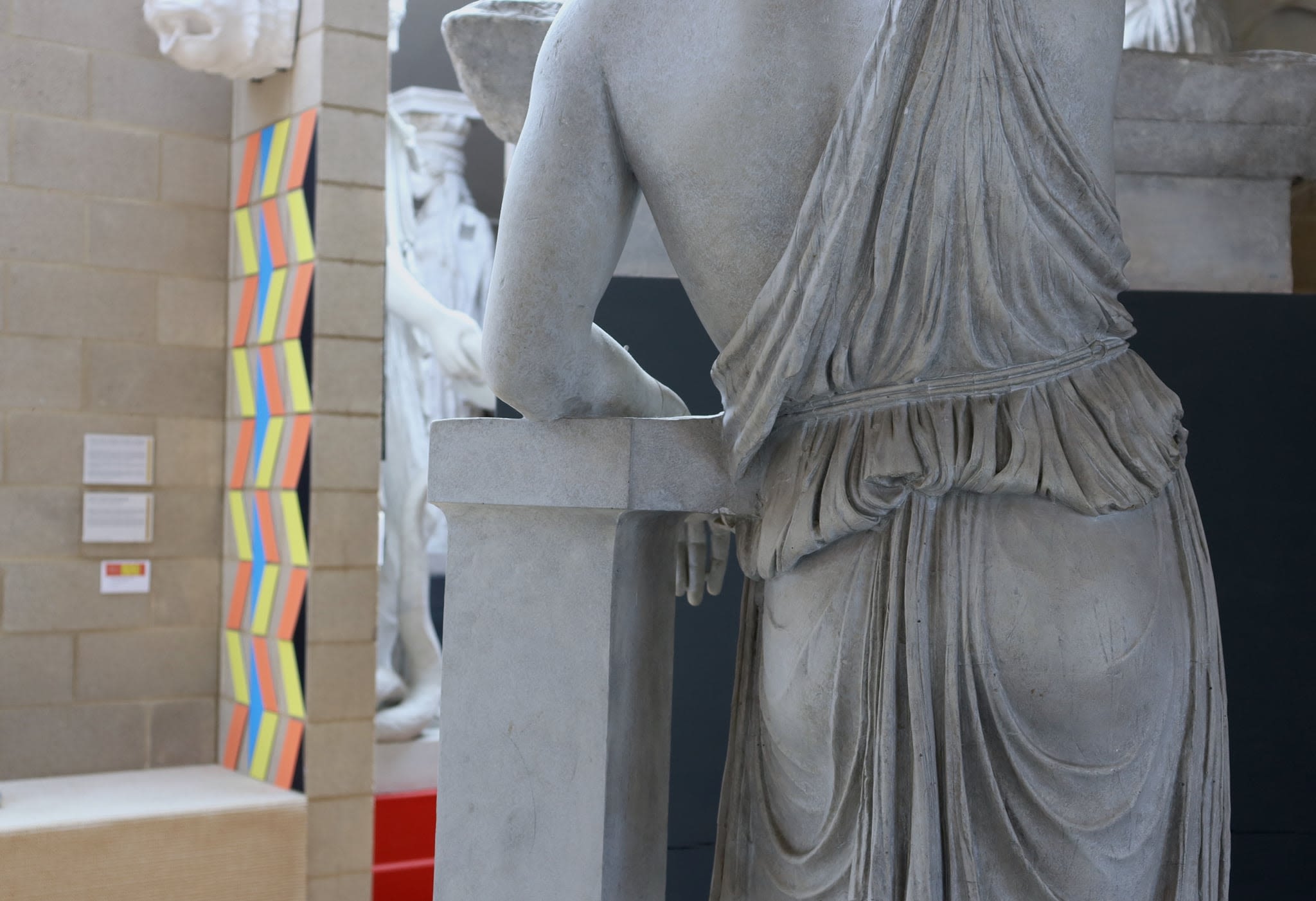 A view of one of the works from behind a statue of a woman