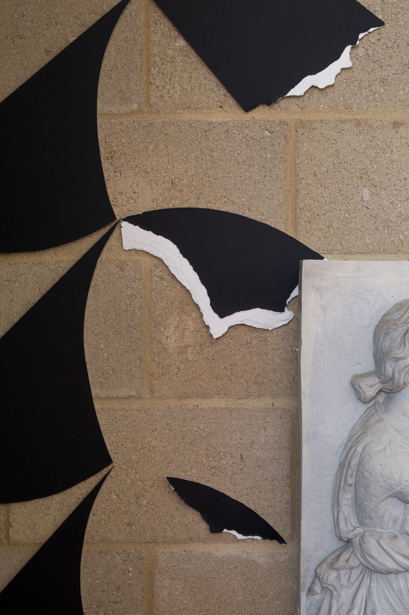 Close up of the black geometric shapes, the edges of some are torn leaving them white and raw.