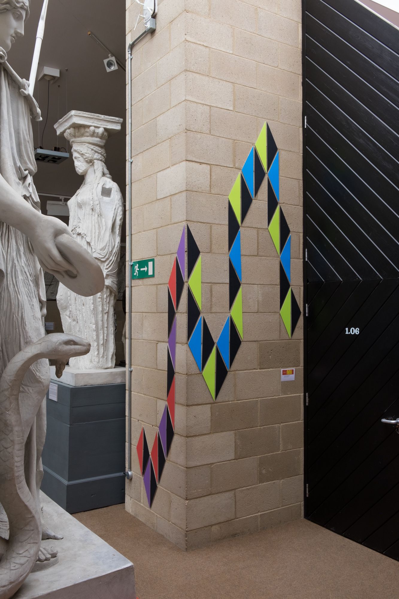 Blue, green, red, purple and black triangles are mounted interlocking up the wall, snaking their way around.