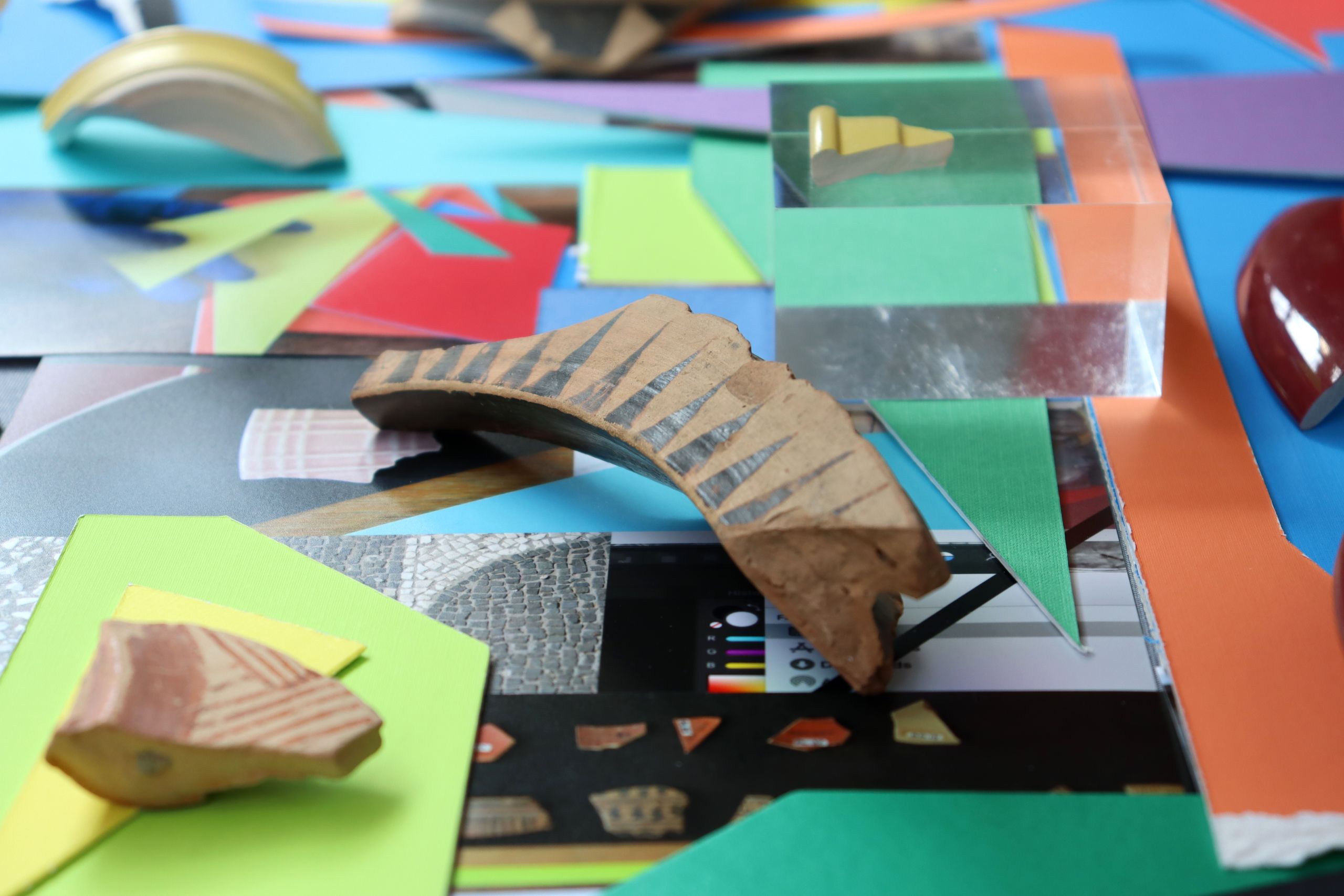 Mixed media: Coloured mountboard is layered with photographs and a piece of ancient Greek pottery