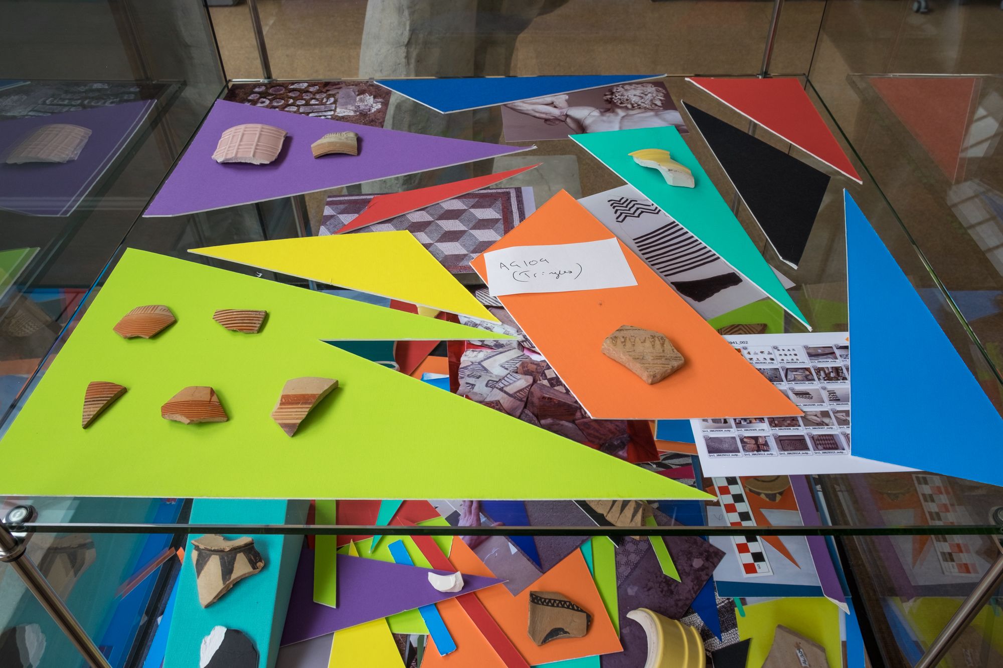 Arrangement of Coloured mountboard, photographs, broken ceramics and ancient sherds.