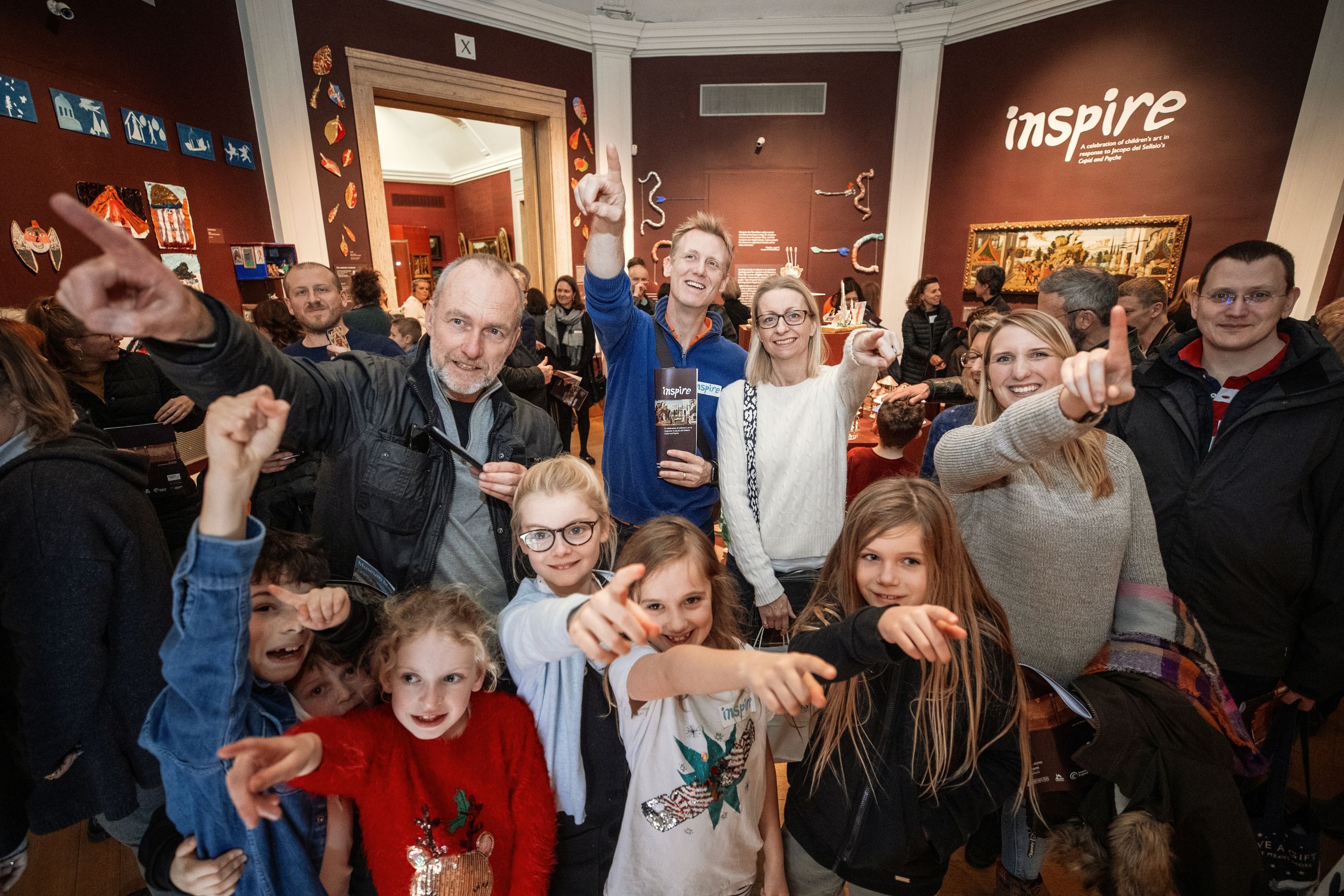 Families point towards the camera in a museum gallery