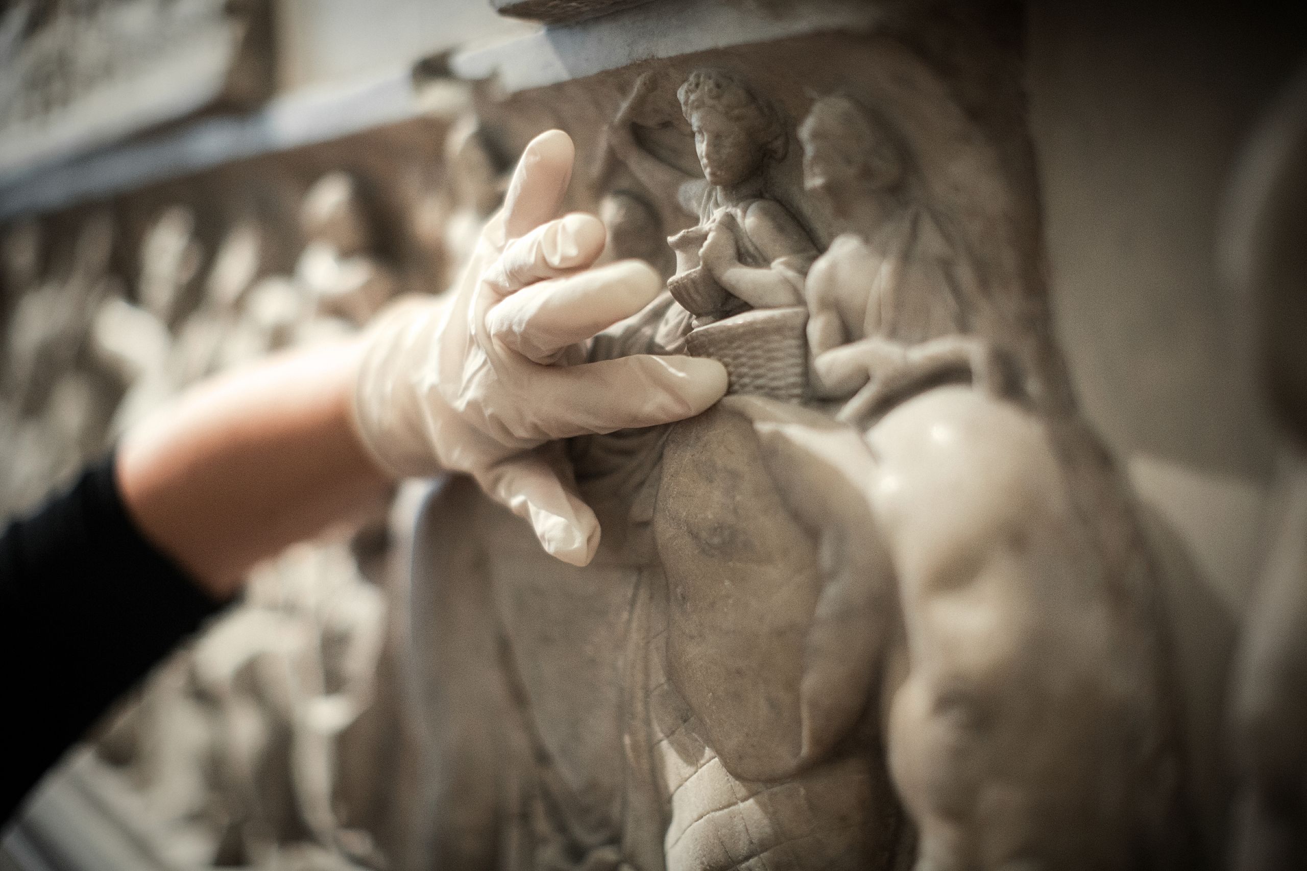 A gloved hand touching an object in a museum