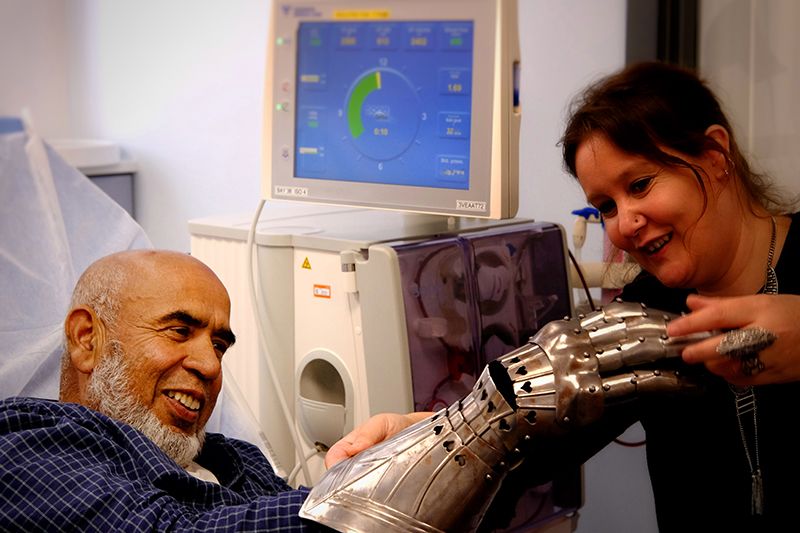 A person in hospital tries on a piece of armour from the Fitzwilliam Museum