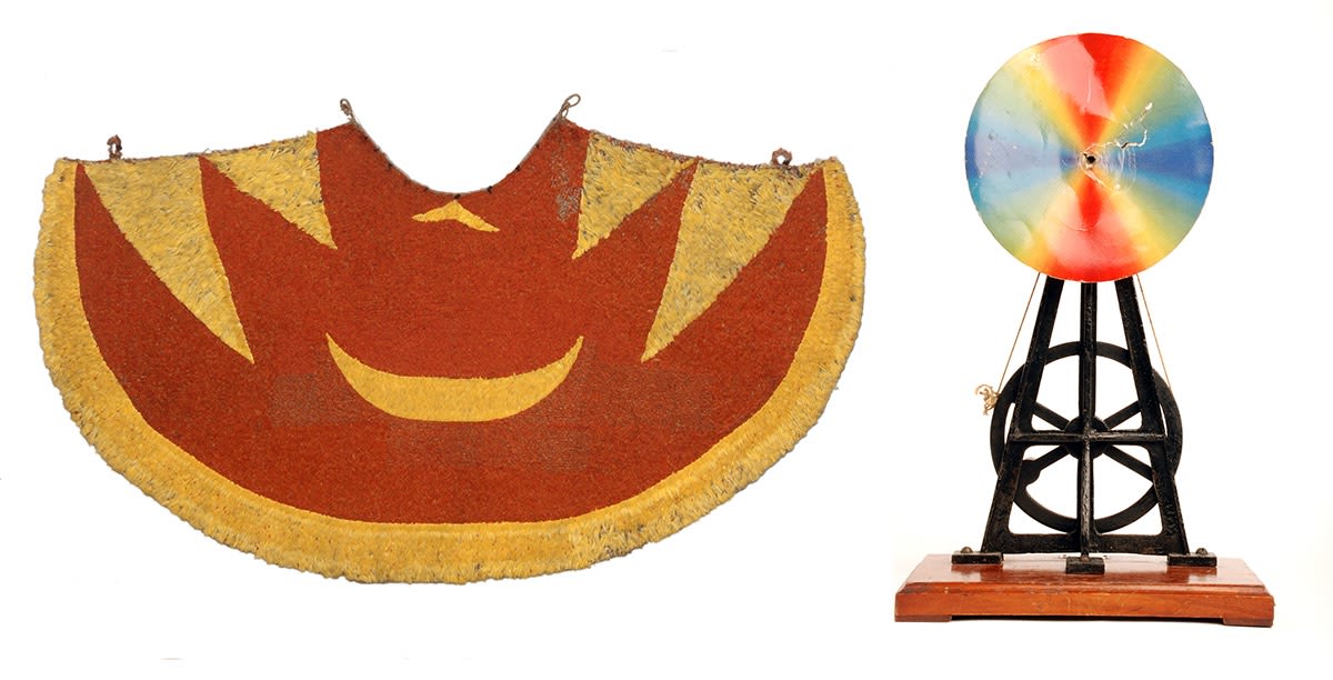 Two objects side by side. A yellow and red feather cloak, shown open, on the left. On the right, a colour wheel with a black and wooden base.