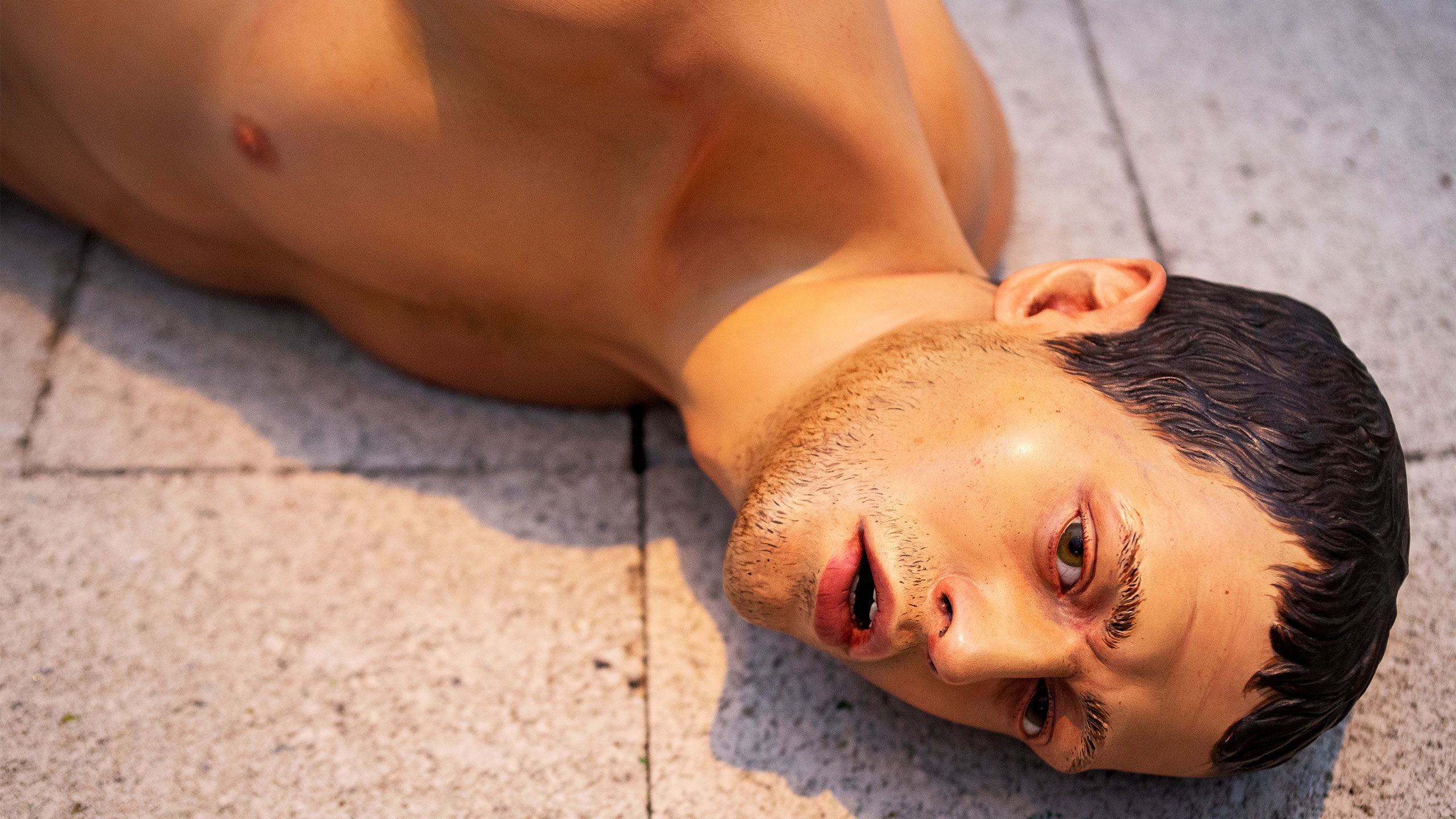 Action 125, an image of an Iraq Prisoner of war made from Limewood, painted, with glass eyes; and concrete breeze blocks (plinth)