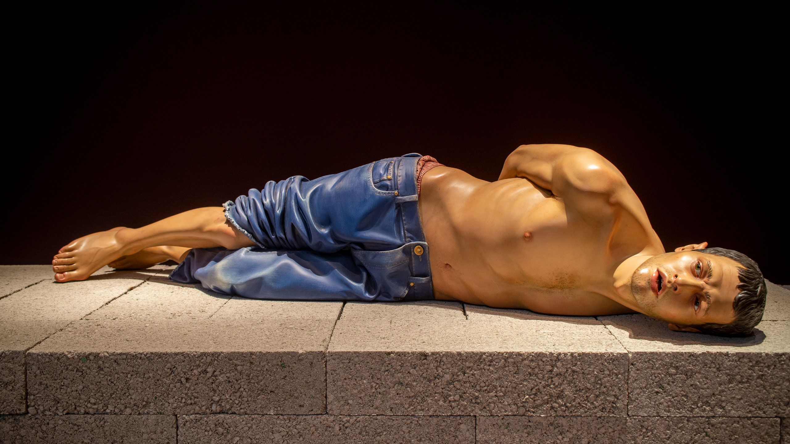 Action 125, an image of an Iraq Prisoner of war made from Limewood, painted, with glass eyes; and concrete breeze blocks (plinth)