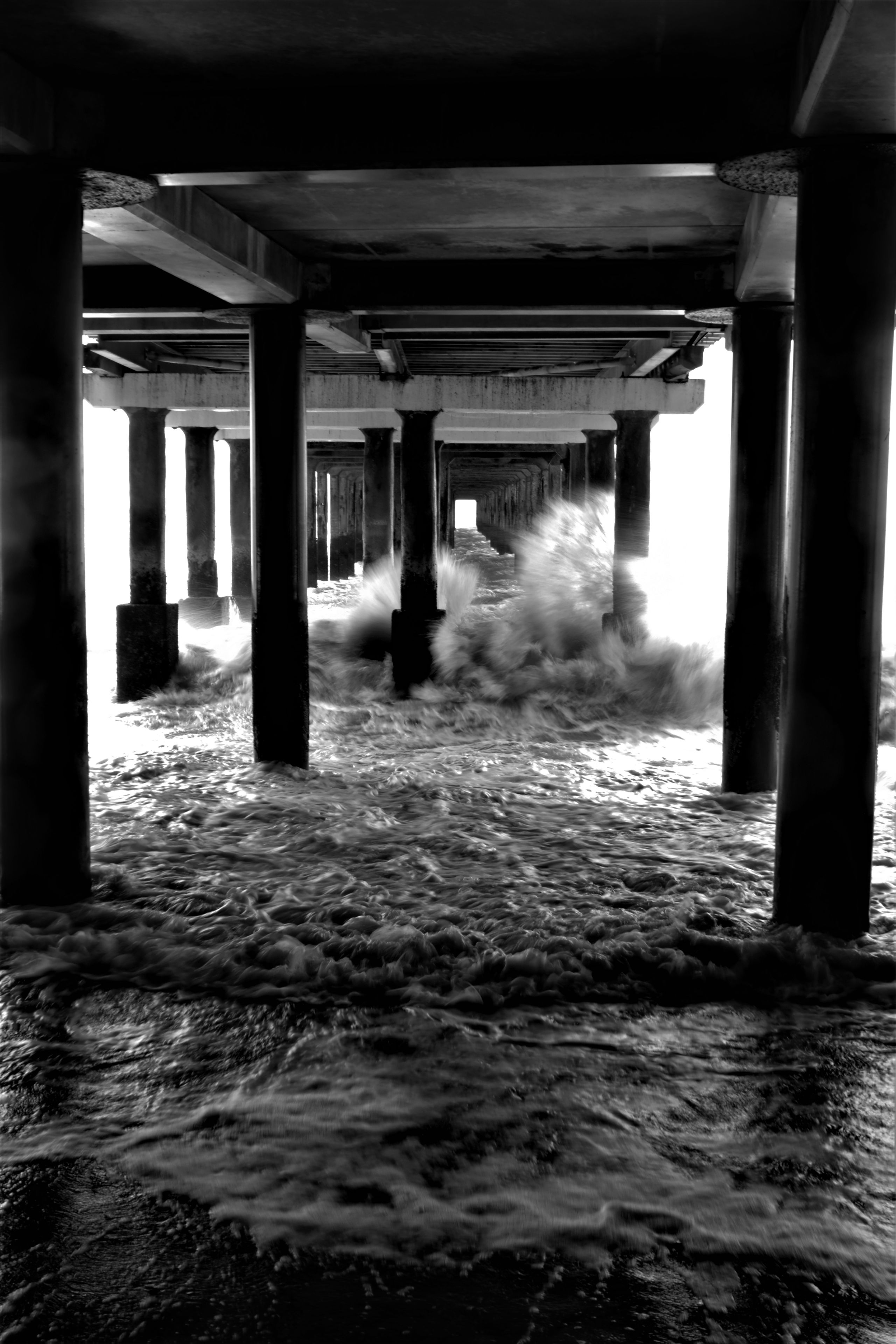 waves hitting the supports of a beach pier